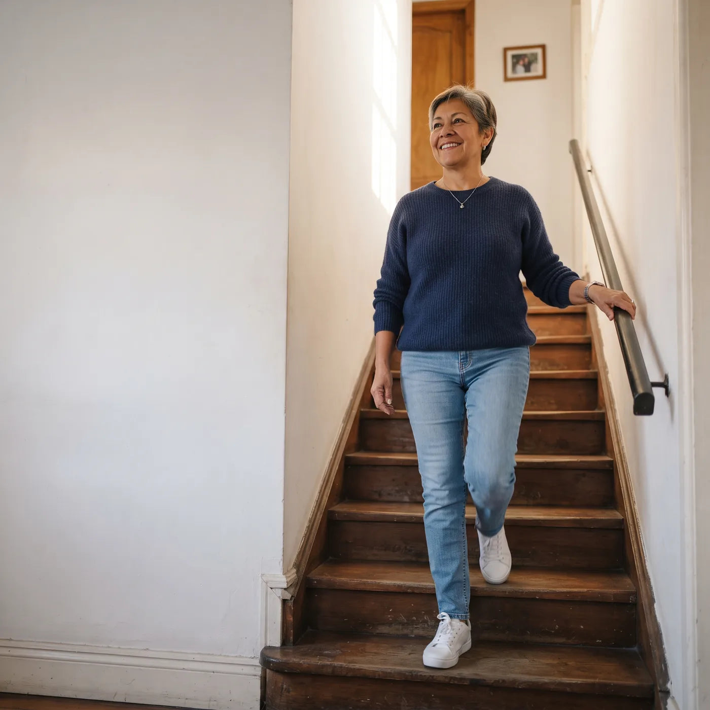 Mujer que baja la escalera de su casa sonriendo